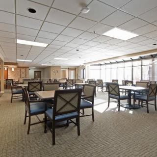A spacious and well-lit dining area with multiple tables and chairs, surrounded by large windows.