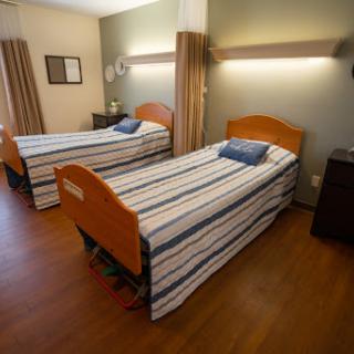 A cozy bedroom featuring two twin beds, complete with striped bedding and warm lighting.