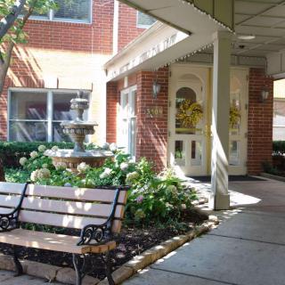 A welcoming entrance with a bench and garden area featuring a fountain.