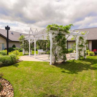 A beautifully landscaped garden featuring a white pergola surrounded by lush greenery.