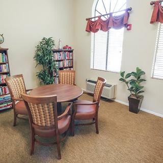 A cozy reading room with a round table, surrounded by chairs and bookshelves.
