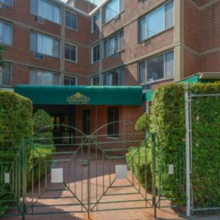 The entrance to a residential building features a gated entry and surrounding greenery.
