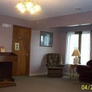A living room with a chair, lamp, and window, featuring carpeted flooring.