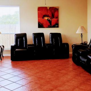 A cozy living room with leather seating and vibrant artwork on the wall.