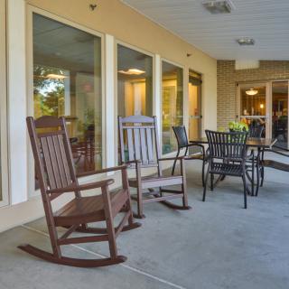 A cozy patio with rocking chairs and a dining table set.