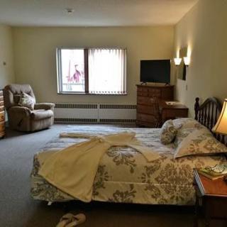 A cozy bedroom with a bed, chair, dresser, and television.