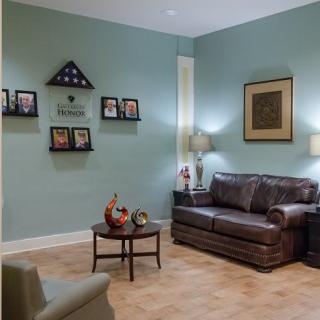 A cozy living room with a leather sofa, lamps, and decorative wall art.