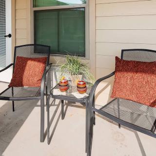 A cozy patio setup with two chairs, a small table, and decorative cushions.
