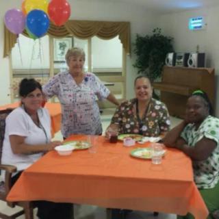 A group of people sitting around a decorated table, enjoying a celebration with balloons.