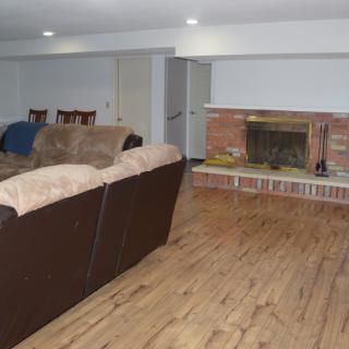 A cozy living room featuring a sofa and a fireplace with wood flooring.