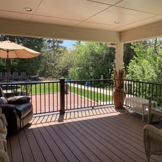 A sunny outdoor patio with comfortable seating overlooking a lush backyard.