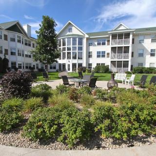 A residential apartment building with well-maintained landscaping and outdoor seating areas.