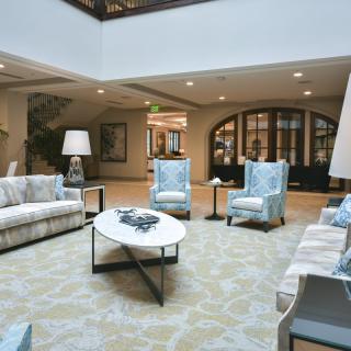A modern lobby seating area with comfortable chairs and sofas around a central coffee table.