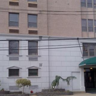 A city building with multiple windows and a green awning over the entrance.