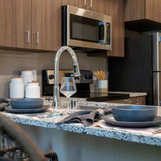 A modern kitchen with wooden cabinets, a granite countertop, and stainless steel appliances.