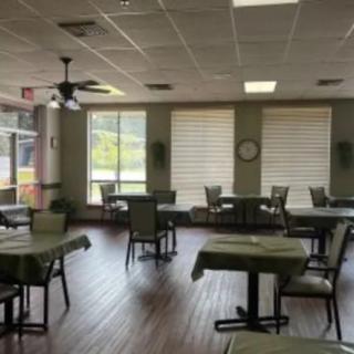 An empty restaurant interior with set tables and large windows.