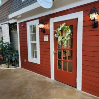 A charming red door adorned with greenery and lanterns, inviting you to enter.
