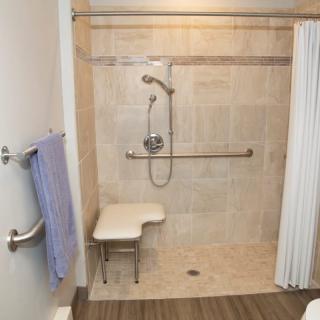 An accessible shower with a chair and grab bars.