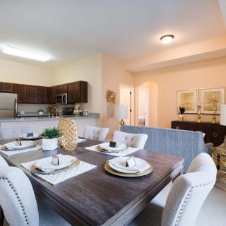 A modern open-concept dining and kitchen area with elegant furnishings and a neatly set table.