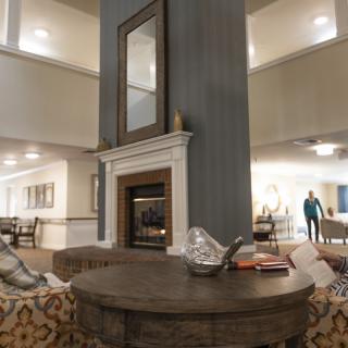 A cozy living room featuring a central fireplace with a large mirror above it, surrounded by comfortable seating and elegant decor.