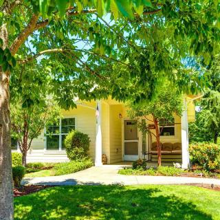 A cozy residential home surrounded by lush greenery and trees on a sunny day.