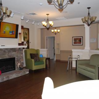 A cozy living room with a fireplace and comfortable seating, enhanced by chandeliers and decor.