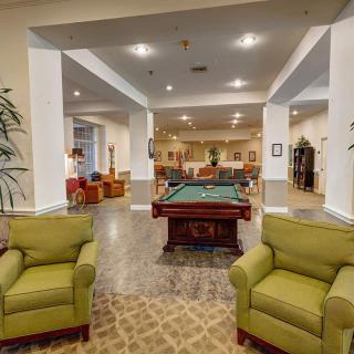 A cozy lounge area featuring a pool table surrounded by comfortable seating and warm lighting.