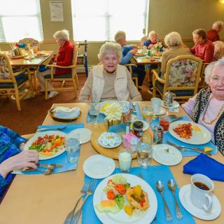 Elderly individuals enjoying a meal together at a community dining setting.
