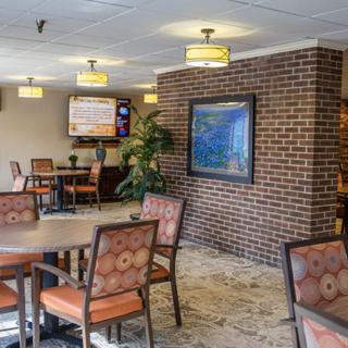 A cozy dining area featuring tables and chairs, with a brick accent wall and warm lighting.