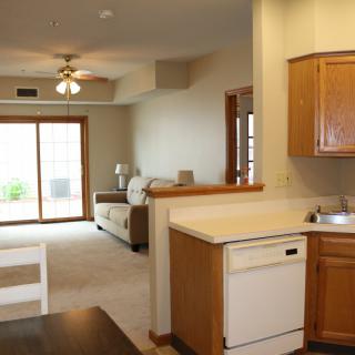 An open-concept kitchen and living room with wood cabinetry and a sliding glass door.