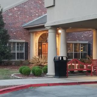 The welcoming entrance of a building featuring outdoor seating and well-kept landscaping.