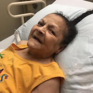 A patient smiles while lying in a hospital bed.