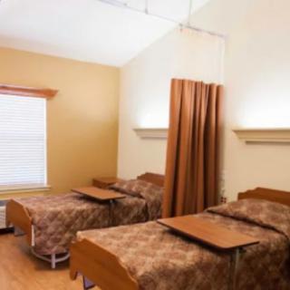 A hospital room with two patient beds separated by a curtain.
