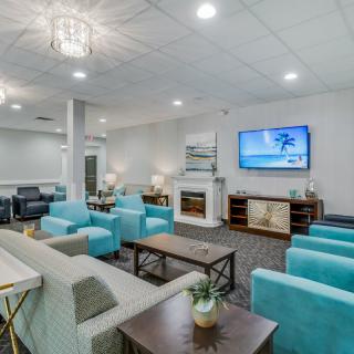 A modern lounge with turquoise chairs and sofas, featuring a TV and stylish decor.