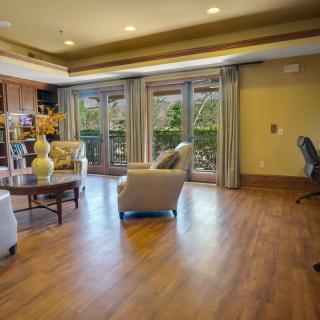 A spacious living room with wood flooring and large windows letting in natural light.