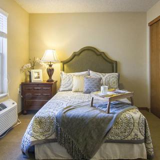 A cozy and stylish bedroom with a neatly made bed, side table, and warm lighting.