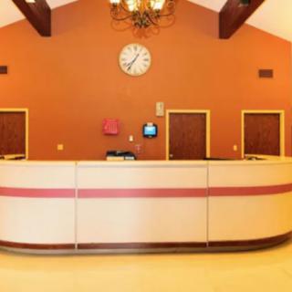 A stylish hotel reception desk with an orange accent wall and a clock.
