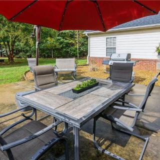 A backyard patio with outdoor furniture and a red umbrella.