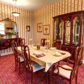 A classic dining room with a wooden table and chairs, surrounded by ornate decor and patterned wallpaper.