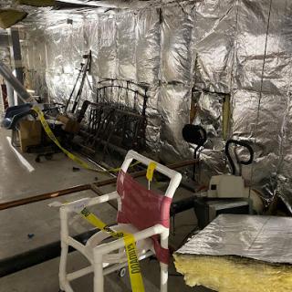 An interior space undergoing renovation, featuring silver insulation and various construction tools.