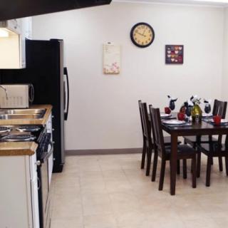 A modern kitchen with a dining area, featuring a table set with chairs and various appliances.