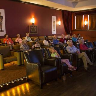 A group of people seated in a small movie theater, attentively watching a film.