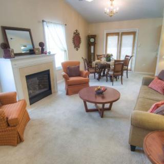 A cozy living room with a fireplace, sofa, chairs, and a dining area.