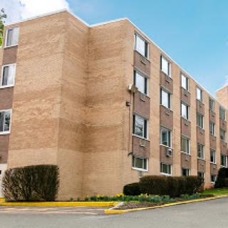 A modern residential apartment building with a brick facade and large windows.