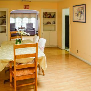 A cozy dining area with a wooden table and chairs, adorned with a flower vase.
