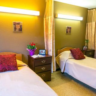 A cozy bedroom with two twin beds, warm lighting, and colorful decor.