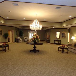 A spacious lobby with a central chandelier, elegant carpet, and furniture arrangement.
