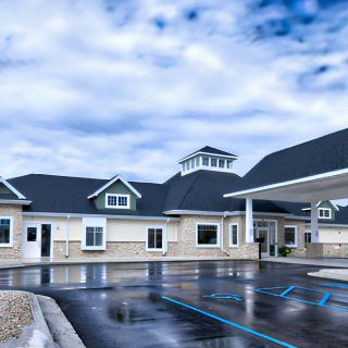 A modern building with a pitched roof and large windows under a cloudy sky.