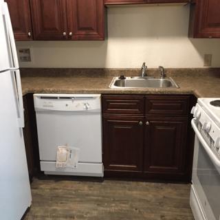 A compact kitchen with wooden cabinets and essential appliances.