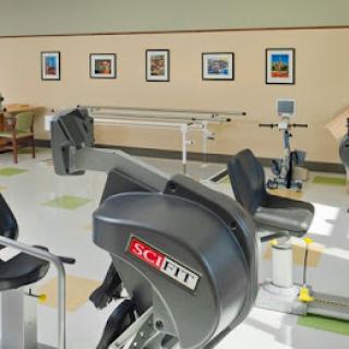 A well-equipped fitness center featuring various exercise machines and framed photographs on the walls.